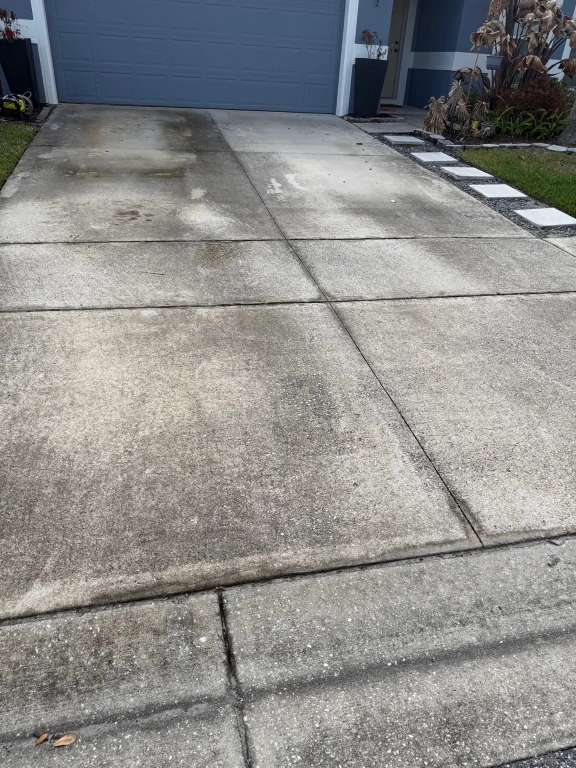 Before: heavily soiled concrete driveway with dark staining at an Orlando home